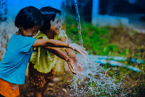 ESG e saneamento básico: Duas crianças indígenas brincam com água